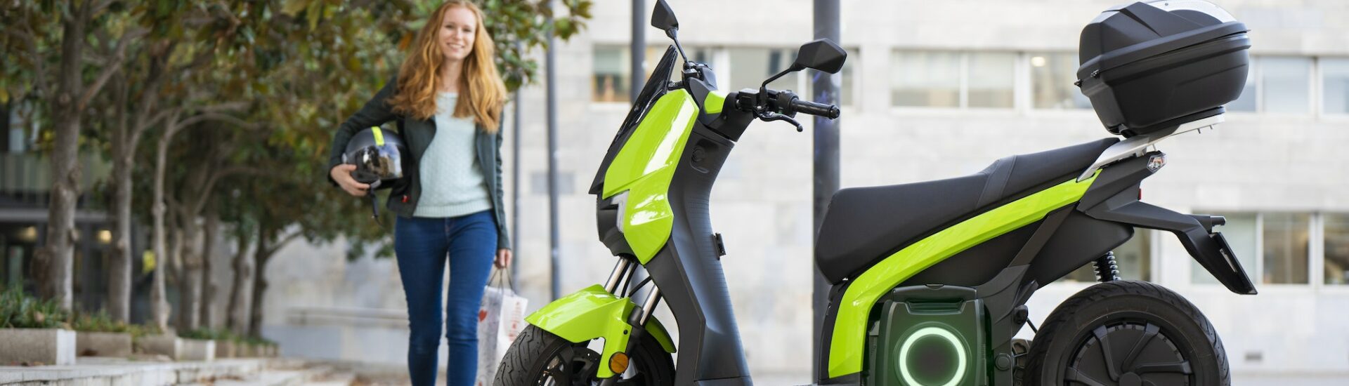 Red-haired woman is going to ride an electric motorbike