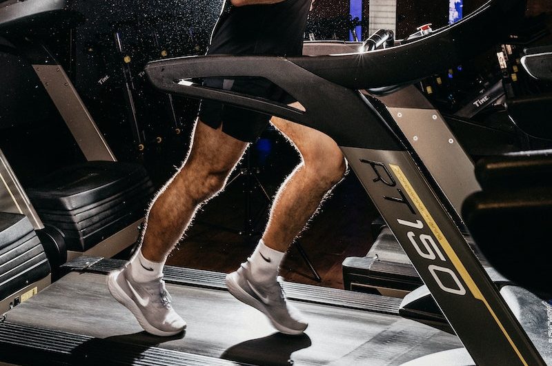 Topless Woman in Black Shorts and Brown Boots Sitting on Black Exercise Equipment