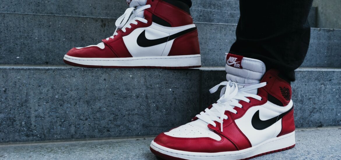 person wearing pair of red-and-white Air Jordan 1 shoes