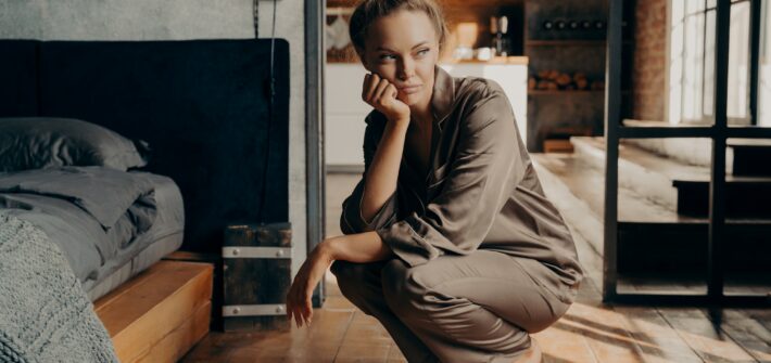 Young dissatisfied unhappy woman crouched over electronic scales